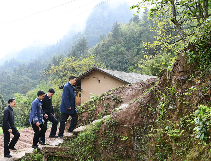 2019年4月15日，在石柱土家族自治县中益乡华溪村，习近平总书记踏着湿滑的石阶登上陡坡，前往贫困户谭登周家看望。